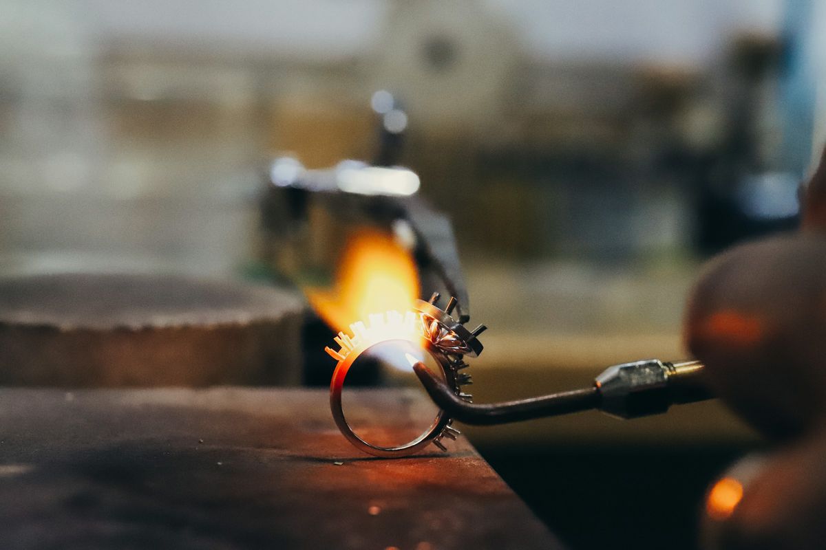 A ring being soldered with a small flame at the jeweller&rsquo;s bench
