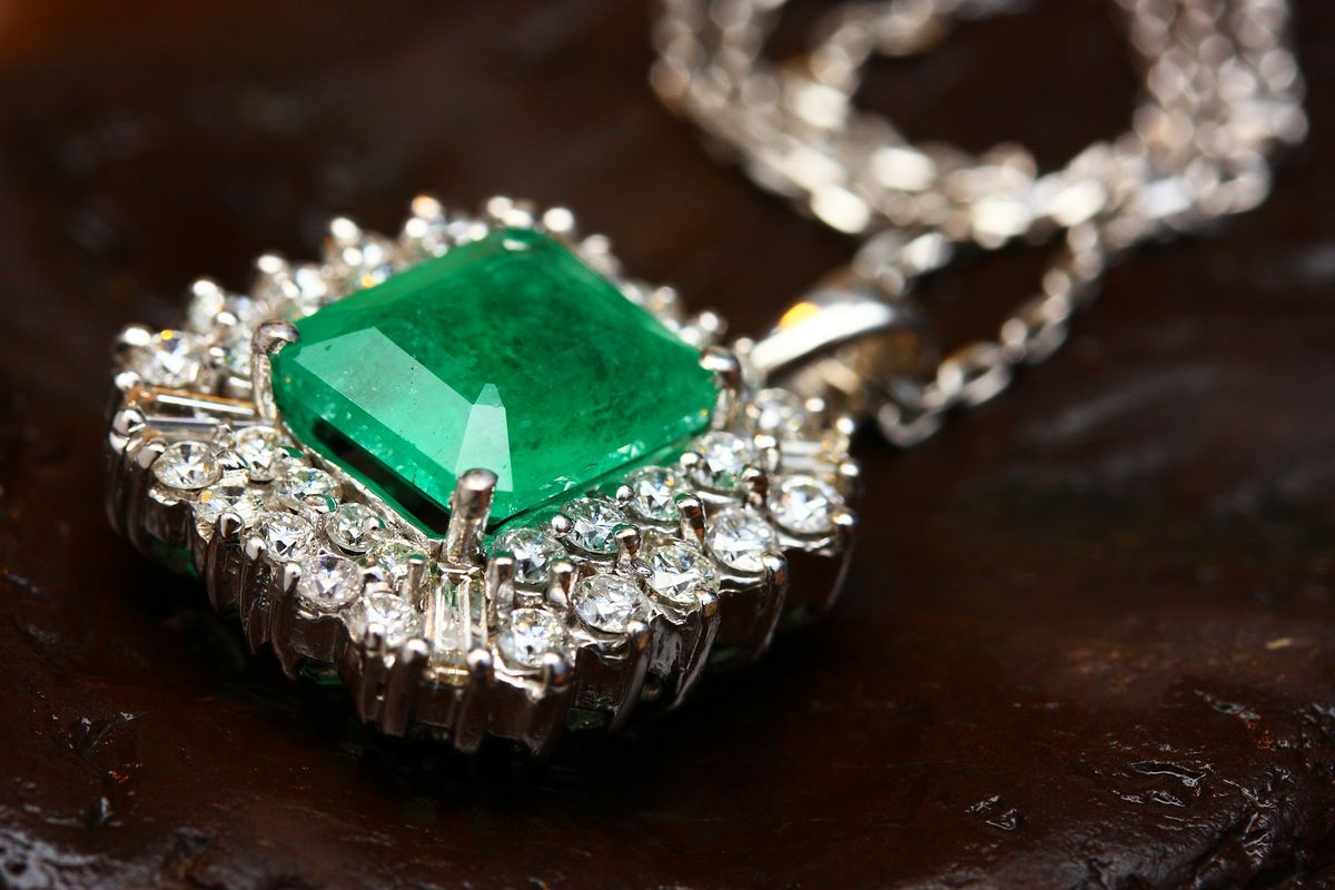 An emerald pendant framed by a halo of diamonds