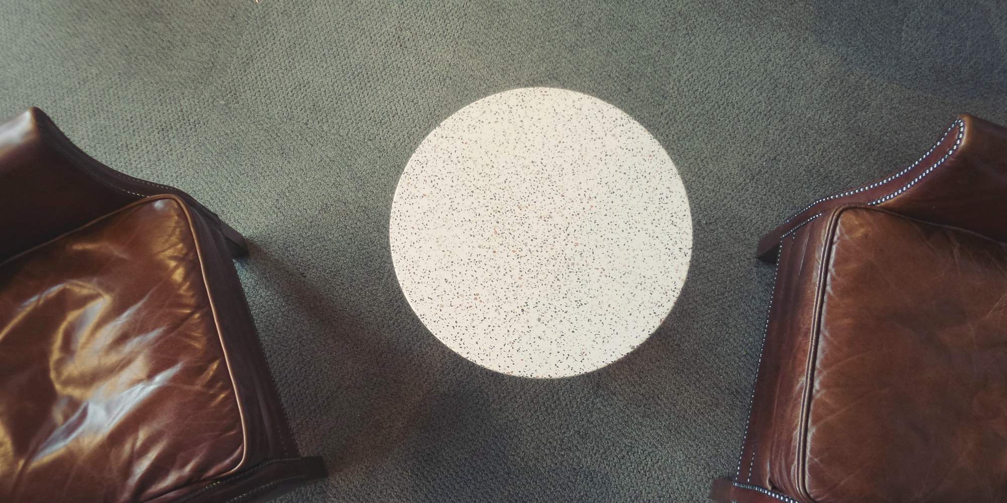 Two leather armchairs facing each other across a round table, seen from above